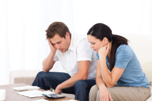Worried couple looking at their bills on the sofa
