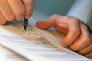Close-up of a mans hands signing on a document
