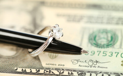 Wedding ring on pen, sitting on money